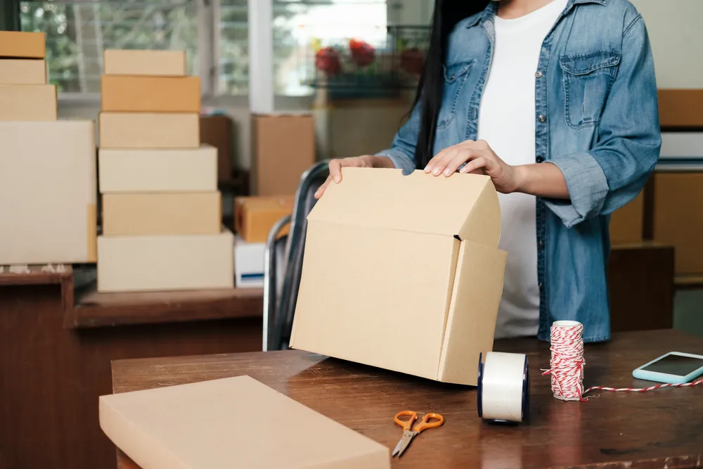 Una pequeña caja armada sobre varias plantillas planas de cajas y empaques de cartón listas para su montaje.